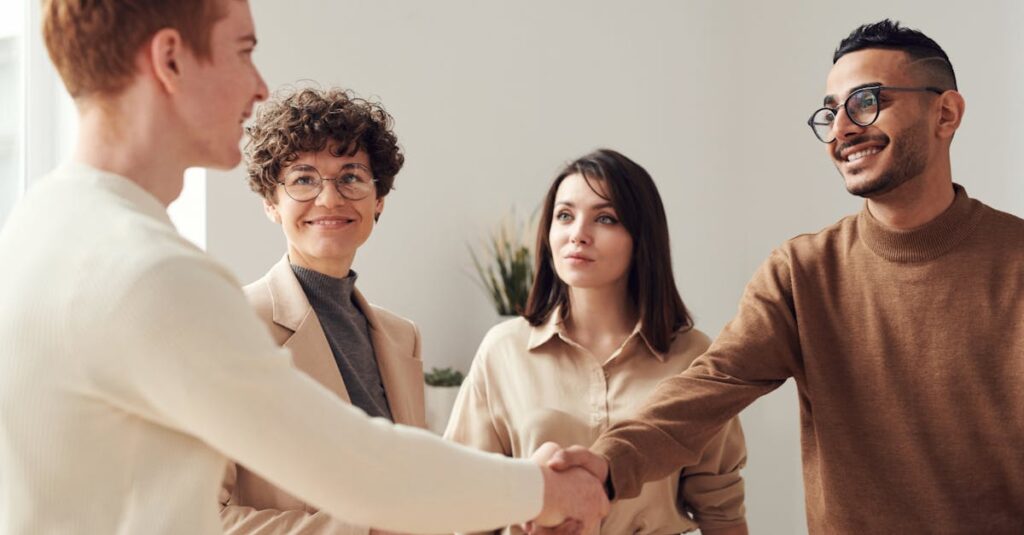 pexels-photo-3184420-3184420 Four colleagues in an office handshake demonstrating teamwork and cooperation.