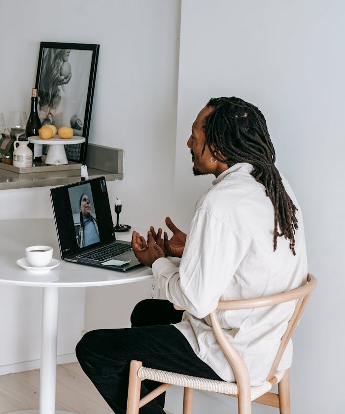 pexels-photo-5699845 African American man having a video call at home with coffee and laptop.